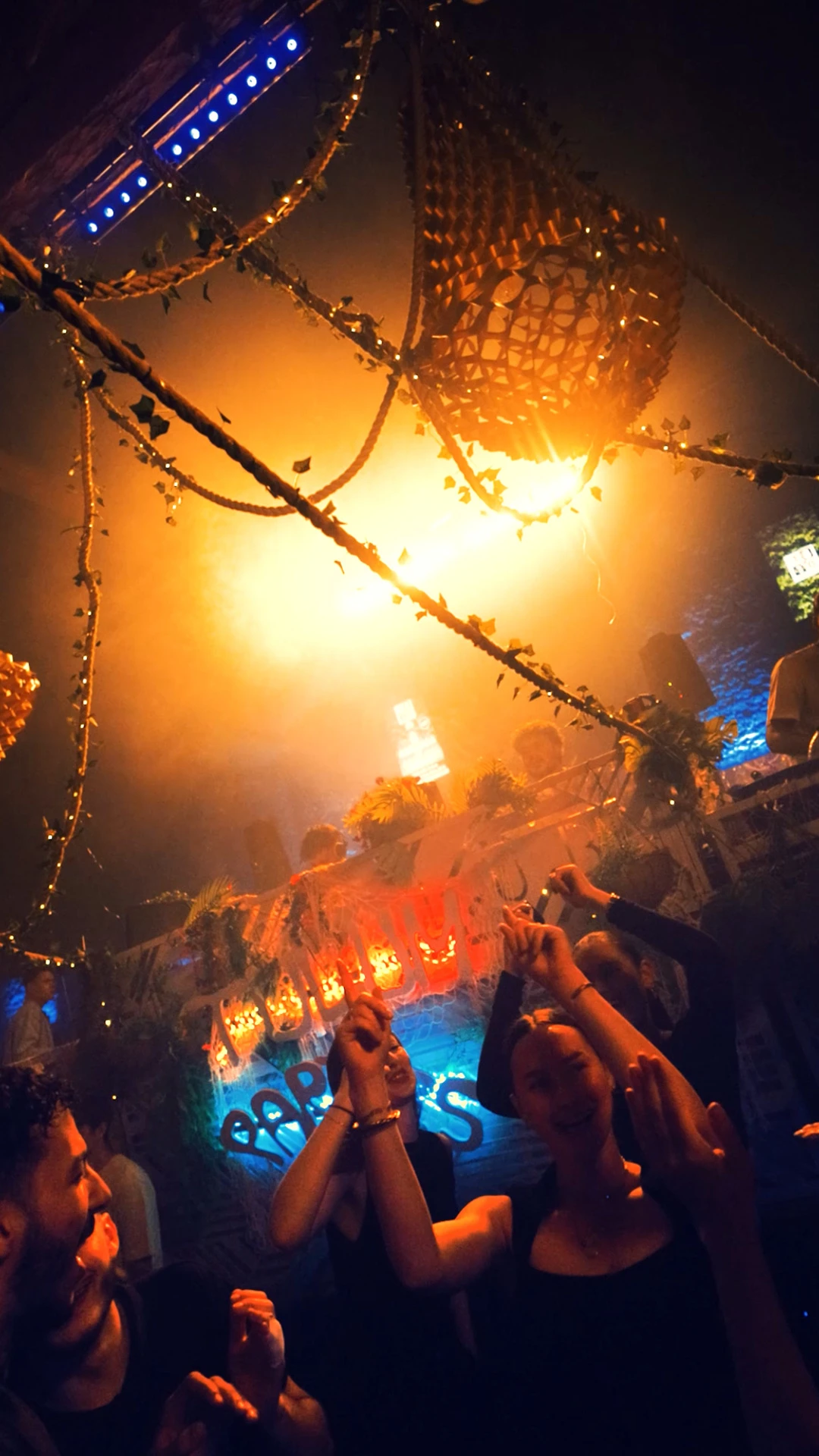 Fête immersive dans une ambiance jungle avec DJ en arrière-plan.