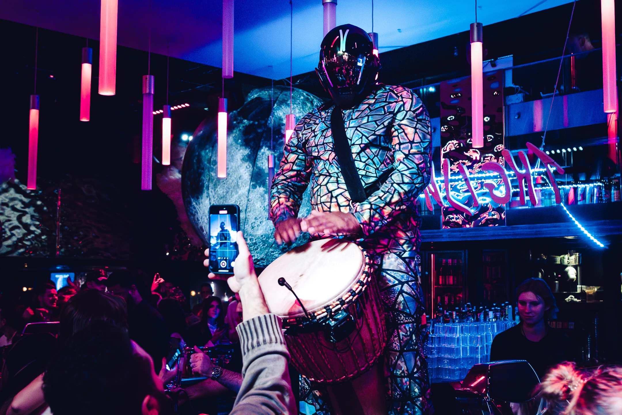 Percussionniste masqué jouant du tambour dans un club.