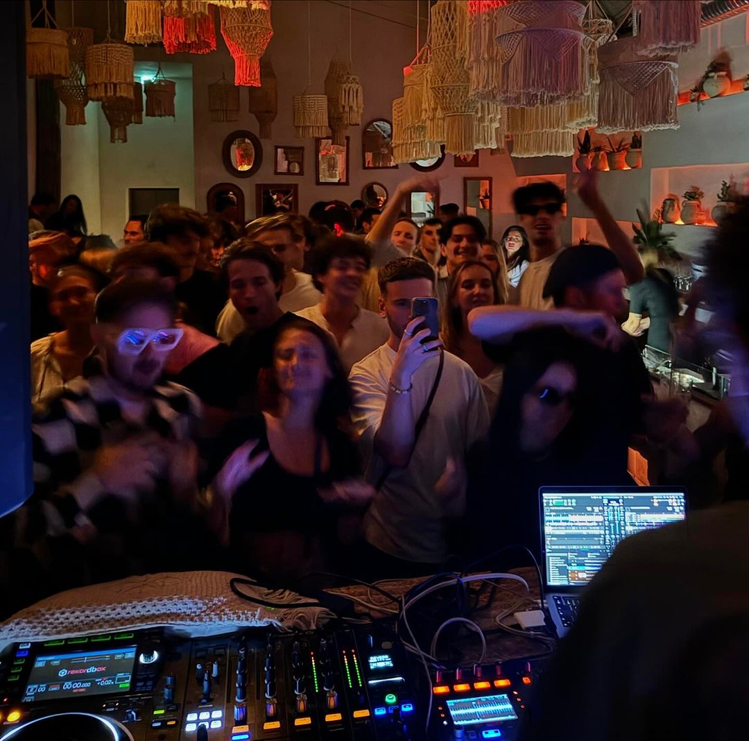 Soirée festive en intérieur avec éclairage tamisé, dj qui mixe, et groupe de personnes qui dansent
