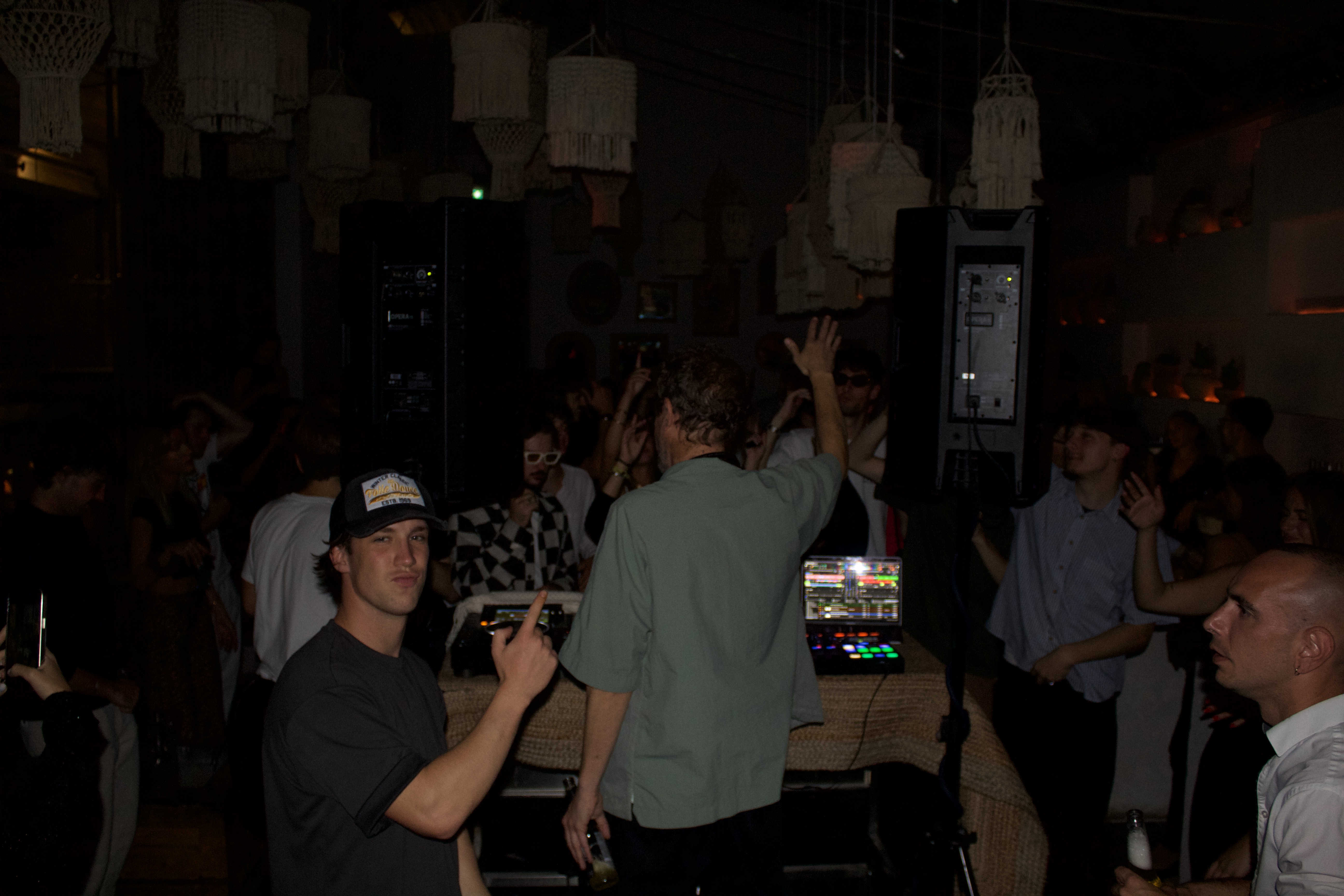 Jeune homme souriant vêtu d'une casquette pointe le DJ.
