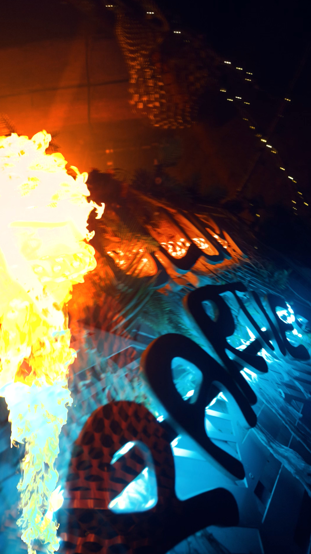 Détail de lettrage lumineux 'PARTIES' sous lumière orange et bleue, effet de flamme et reflets.