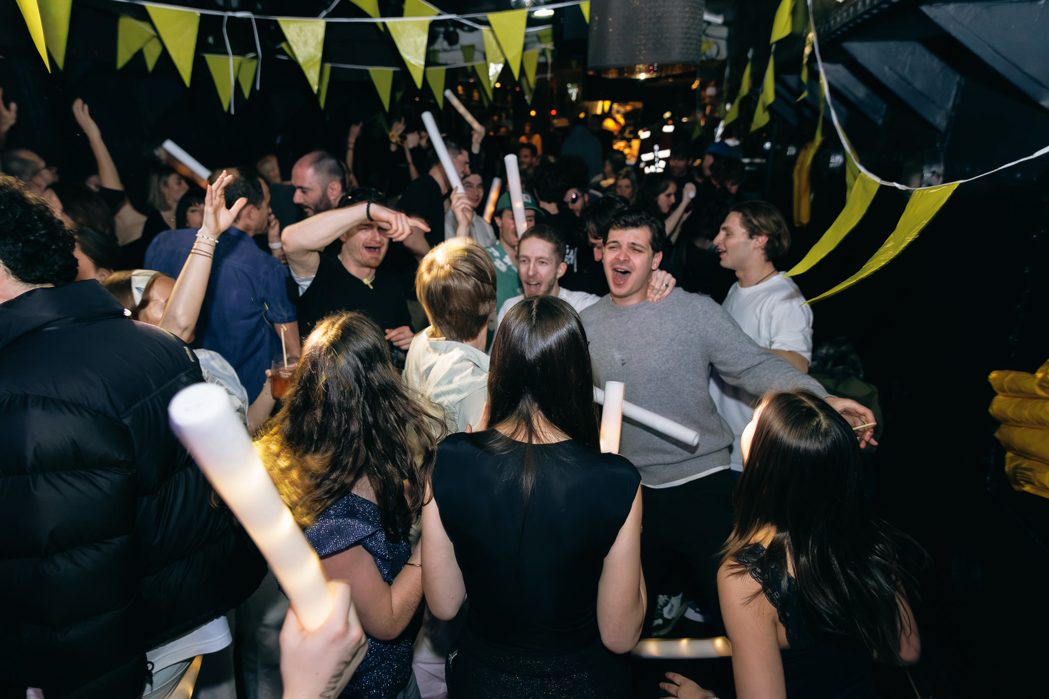 Foule de personnes s'amusant dans une ambiance conviviale avec des drapeaux jaunes au plafond